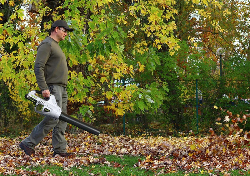 Man using the cordless Warrior leaf blower to clear a heavy patch of dead leaves